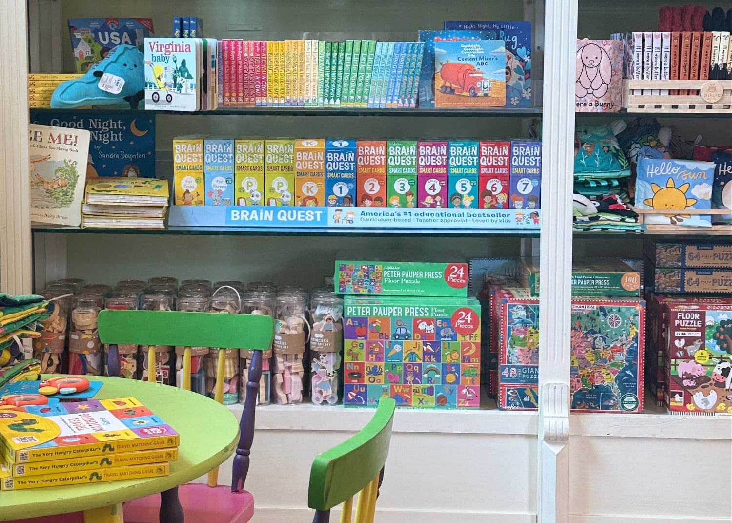Children's books on shelves with a small table and chairs in a room.