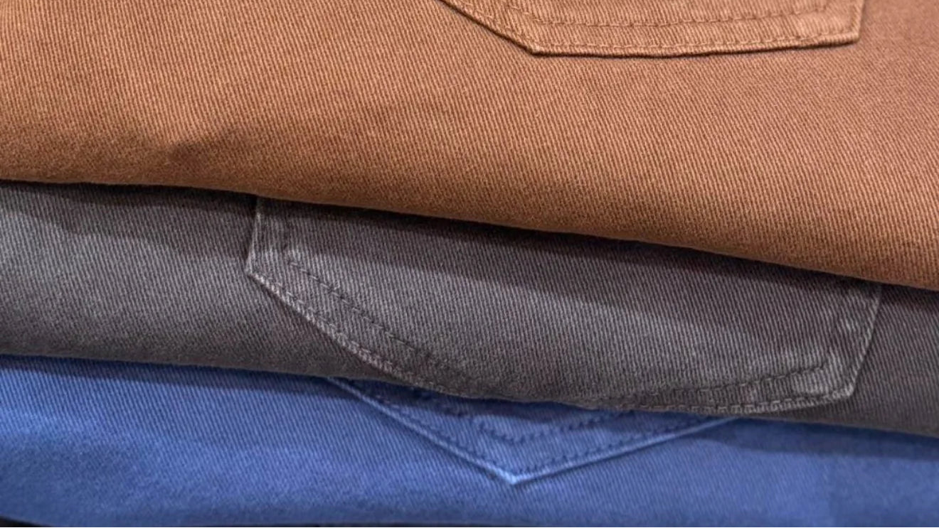 Stack of brown, gray, and blue pants with a visible brand tag: Ballin