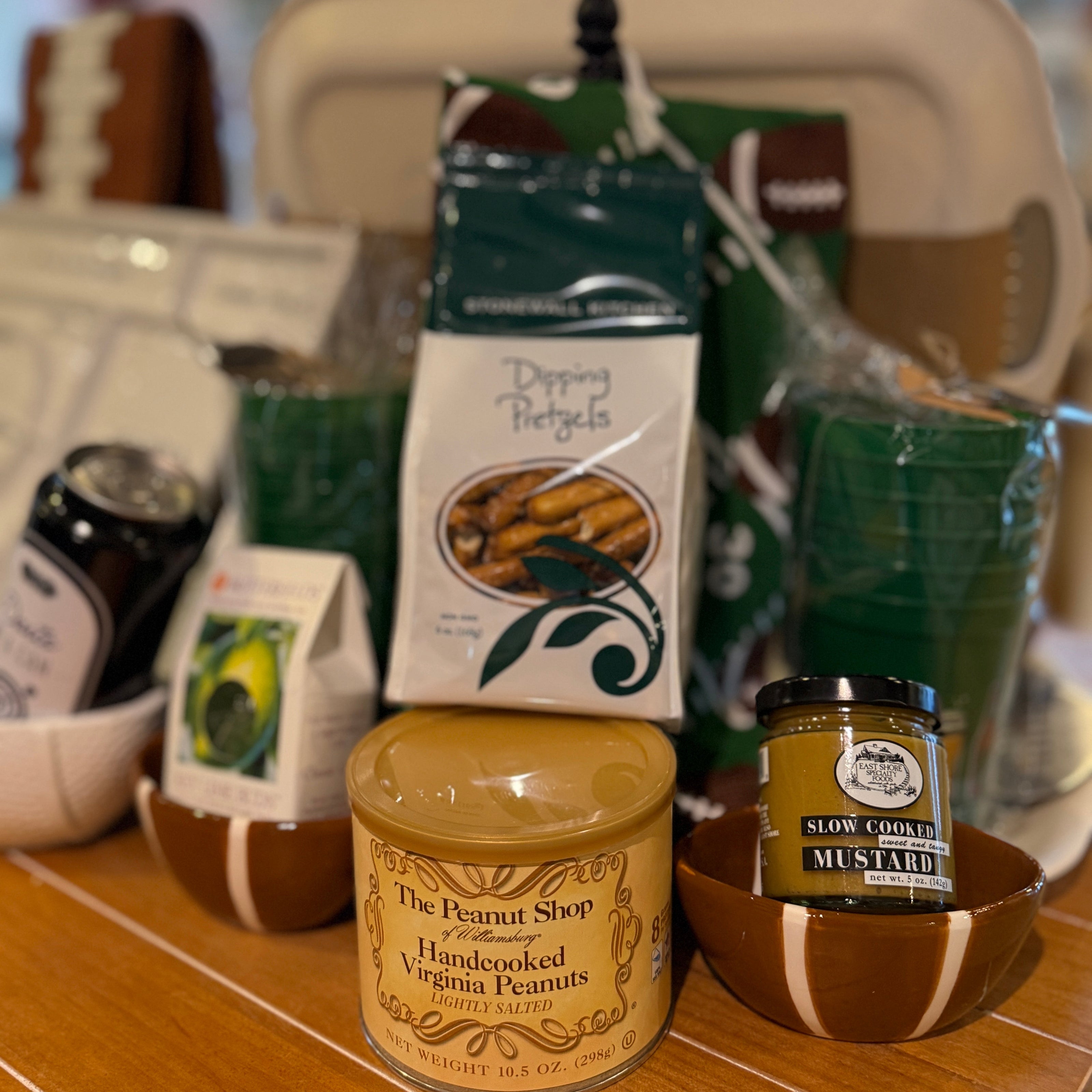 Assorted food items including a jar of peanut butter and a jar of mustard on a wooden surface.