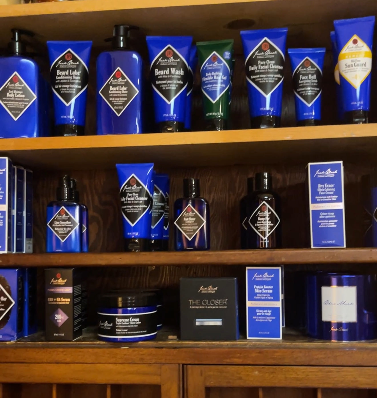 Wooden shelf with various Jack Black grooming products on a wooden background
